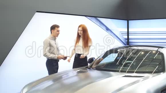 白种人年轻夫妇选择豪华汽车在汽车经销商看看内部和汽车特点视频的预览图