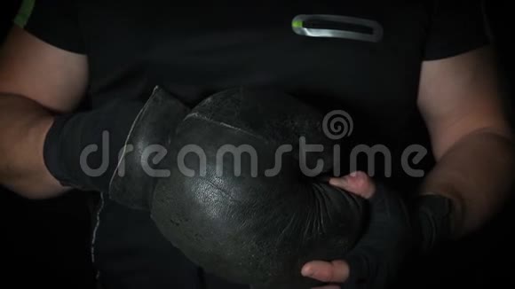穿着黑色制服的运动员双手戴着非常旧的皮拳击手套视频的预览图