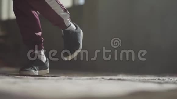 一个穿着运动鞋的专业舞者的脚在废弃的房子里尘土飞扬的混凝土地板上跳舞视频的预览图