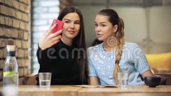 两个女朋友在咖啡馆里拍手机自拍视频的预览图