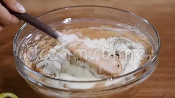 用刮刀在玻璃碗中搅拌巧克力面团的女性手的顶部视图视频的预览图