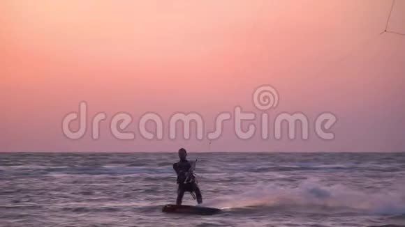 黎明时男子控制着一只明亮的训练风筝漂浮在海里视频的预览图