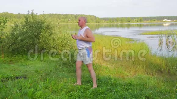 一位中年男子早上在湖边做呼吸练习瑜伽视频的预览图