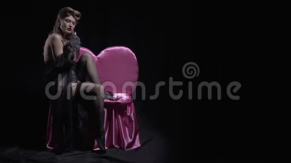 50多岁的年轻金发女郎正在摆姿势坐在一张4k的粉红色沙发上视频的预览图