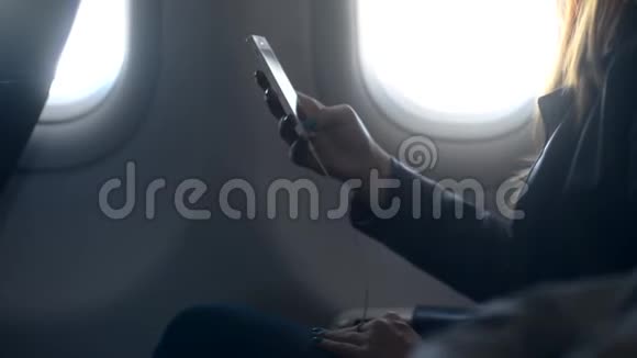 忙碌的女人手里拿着电话坐在飞机上视频的预览图