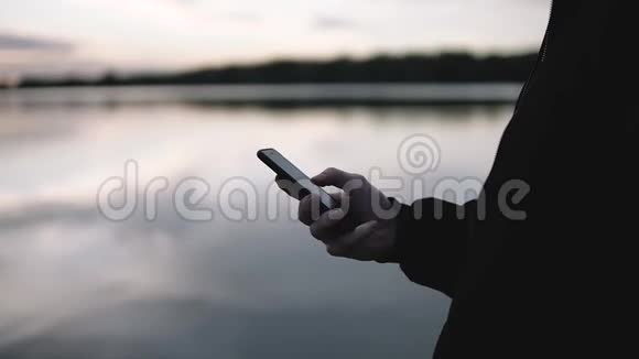 在美丽的夕阳下商人手里拿着一部智能手机视频的预览图