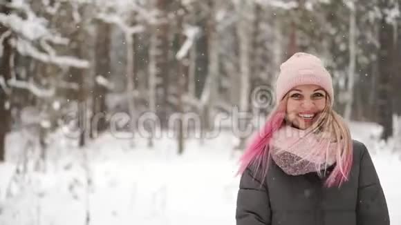 慢动作冬天的女人在树林里看着雪花飘落微笑着看着天空直接走进了天空视频的预览图