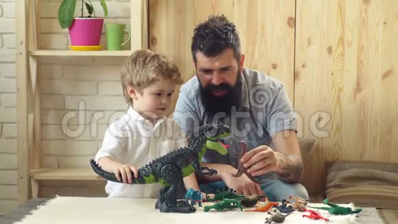 父子俩玩恐龙可爱的小孩和长胡子的父亲玩塑料恐龙父亲视频的预览图