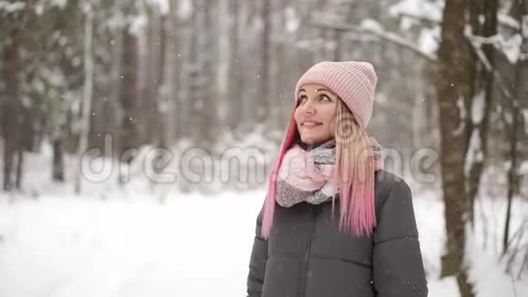 慢动作冬天的女人在树林里看着雪花飘落微笑着看着天空直接走进了天空视频的预览图