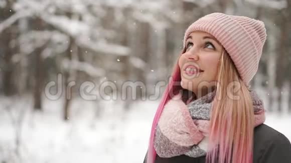 慢动作冬天的女人在树林里看着雪花飘落微笑着看着天空直接走进了天空视频的预览图