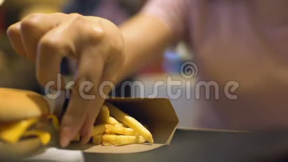 女士用手从桌上的纸箱里拿出炸土豆胆固醇盐视频的预览图