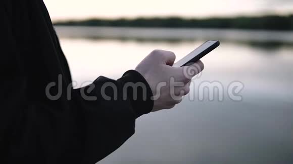 商务经理手里拿着一部智能手机手里拿着一部美丽的日落视频的预览图