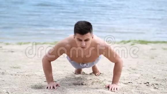 健身男子做俯卧撑在海滩上锻炼身体视频的预览图