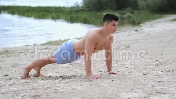 健身男子做俯卧撑在海滩上锻炼身体视频的预览图