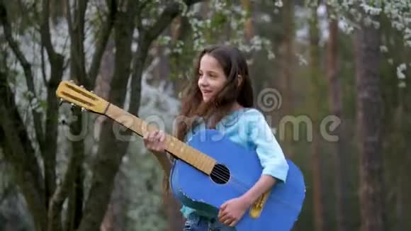 两个有趣的女孩正在玩蓝色吉他与金发在公园摇头的乐趣春天的心情微笑视频的预览图