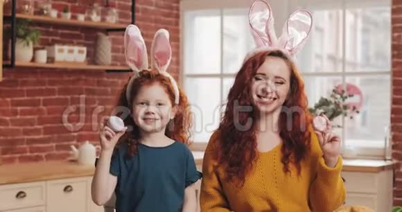 她的母亲在厨房背景上玩复活节彩蛋这是一个快乐的红头发小女孩的肖像他们是视频的预览图