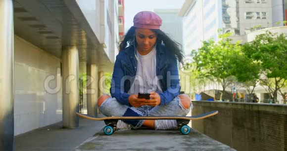 城市中使用手机玩滑板的女舞者视频的预览图
