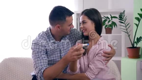 健康的家庭夫妻有孕检结果阳性在家中幸福地拥抱在一起视频的预览图