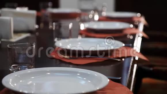 一家著名餐厅的餐桌设置干净和白色的盘子棕色餐巾纸上的玻璃杯和抛光的木制视频的预览图