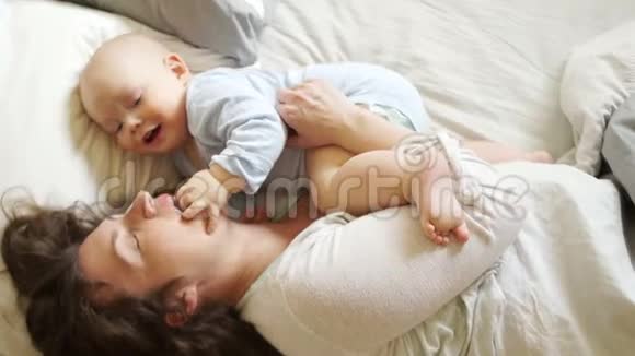 成熟的妈妈陪躺在床上的宝宝玩孩子把手指伸进妈妈的嘴里发育视频的预览图