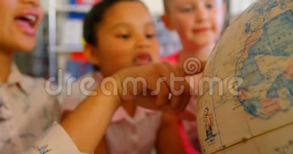 亚洲女教师在学校图书馆的桌子上教孩子们有关地球的知识视频的预览图