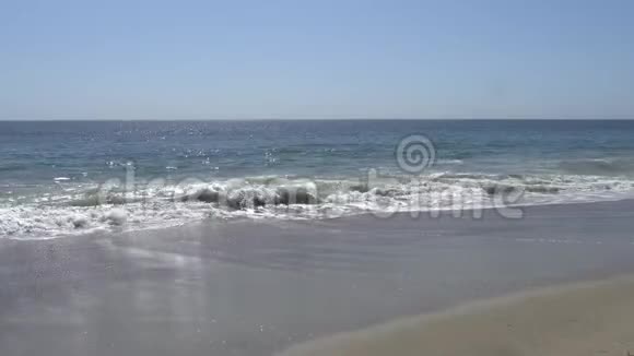 太平洋的波浪在加州马里布海滩的岸边拍打沙滩上温暖阳光的夏日视频的预览图