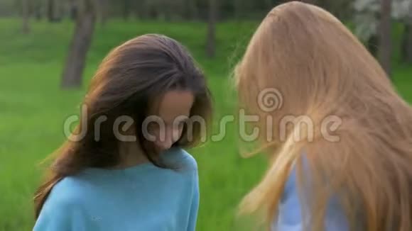 两个快乐的小女朋友金发和棕色头发梳你的头发户外吹着长长的头发视频的预览图