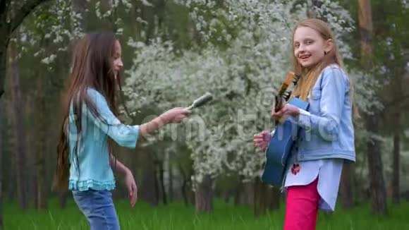 孩子们女孩傻瓜一起唱歌一起跳舞弹吉他在春天的林地里玩得开心视频的预览图