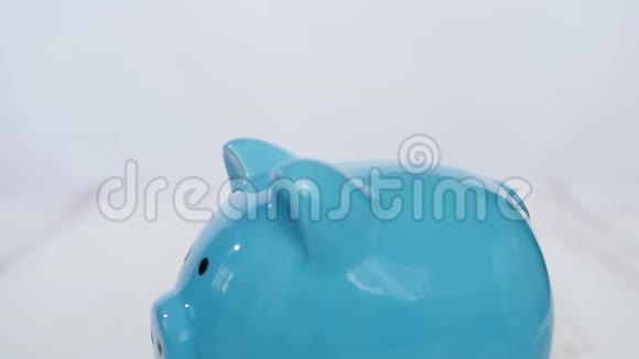 一个小孩把钱币放在白色背景的储蓄罐里视频的预览图