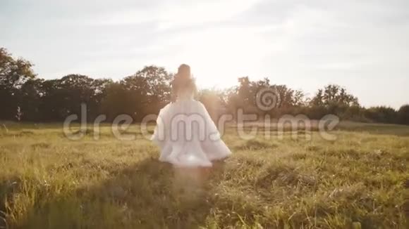 快乐无忧无虑的新娘在阳光下奔跑在大自然上旋转视频的预览图