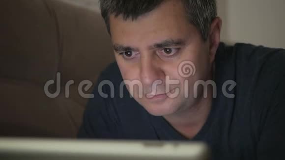 一个男人躺在一张沙发上微笑着看着一台电子平板电脑脸上的情绪视频的预览图