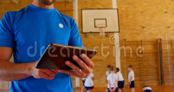 4k学校篮球场上使用数码平板电脑的篮球教练视频的预览图