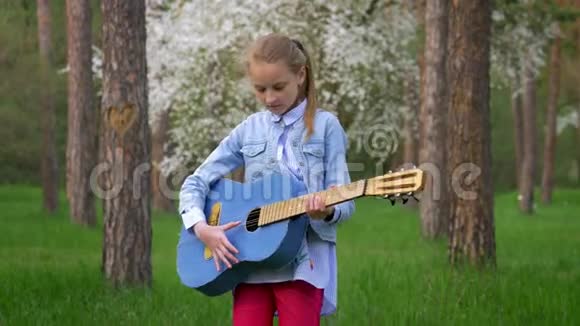 白人小女孩在公园弹吉他视频的预览图