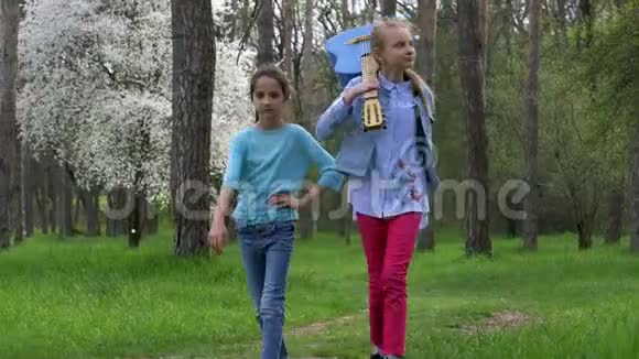 春天在公园里散步两个戴着吉他的白种人女朋友在森林小径上散步概念视频的预览图