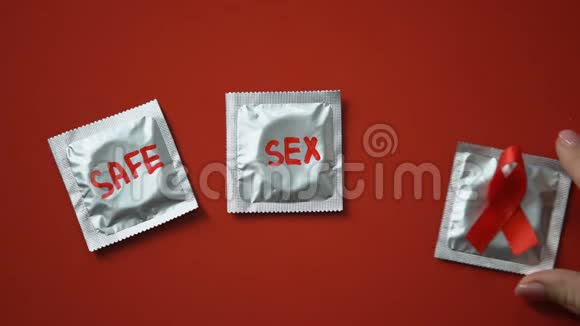 安全的性言语和红丝带在红色背景的避孕套上抗艾滋病和艾滋病毒视频的预览图