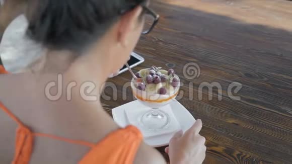 特写镜头戴眼镜的女人坐在海边的咖啡馆里吃甜点视频的预览图
