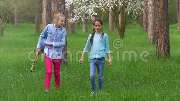 迷人的小女朋友在公园散步两个十几岁的女朋友玩得开心和微笑金发和棕色头发视频的预览图
