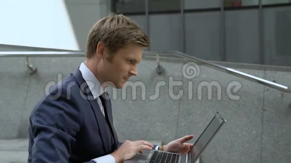 幸运的商人用笔记本电脑检查股市坐在户外的楼梯上视频的预览图
