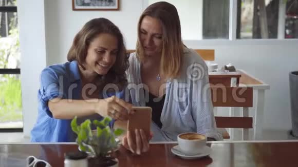 两个女人在咖啡馆里用智能手机分享咖啡视频的预览图