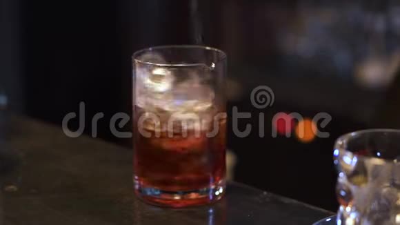 酒保在酒吧里做鸡尾酒酒精手把酒精和冰块混合在玻璃里夜生活视频的预览图