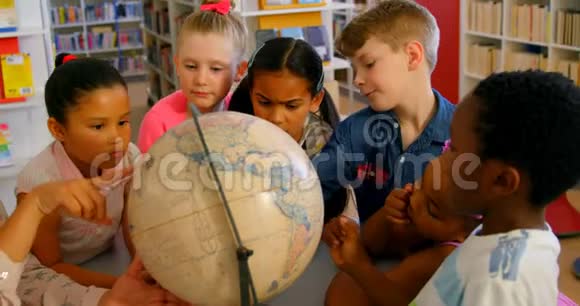 亚洲女教师在学校图书馆的桌子上教孩子们有关地球的知识视频的预览图