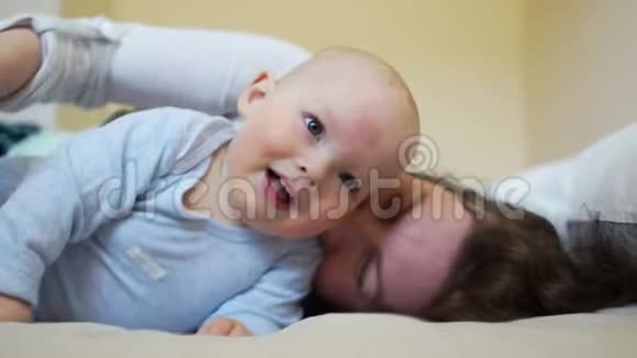 一岁的快乐宝宝和妈妈躺在床上大笑视频的预览图