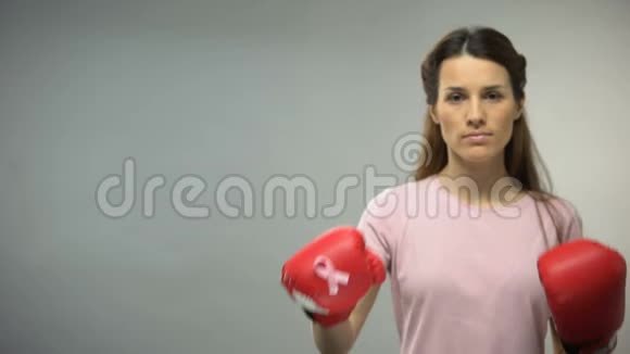 戴着粉红色丝带的拳击手套的女士对抗乳腺癌提高社会意识视频的预览图