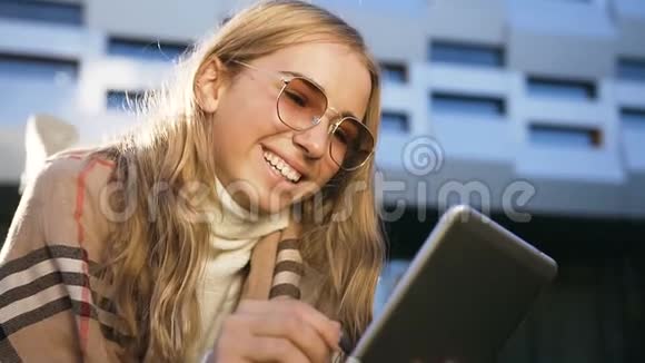 特写镜头可爱的微笑女孩戴着太阳镜使用平板电脑与人聊天的背景视频的预览图