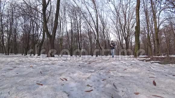 冬天的一天一个人穿过一个下雪的公园通过电话交谈视频的预览图