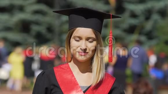 美丽的年轻女子穿着学术服装寻找镜头成功的毕业生视频的预览图
