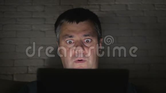 那个人惊恐地看着一间漆黑的房间里的平板电脑屏幕头部和面部特写视频的预览图