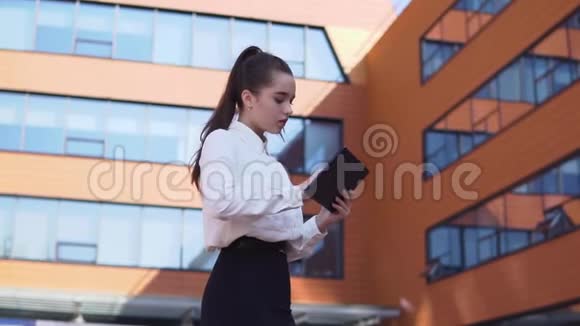 商务女孩站在商务大楼附近手里拿着一块平板电脑高清高清视频的预览图