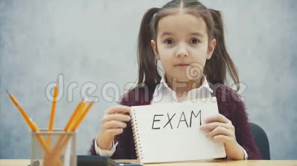 年轻的头发硬的女孩坐在桌子旁在这题词的手中考试视频的预览图