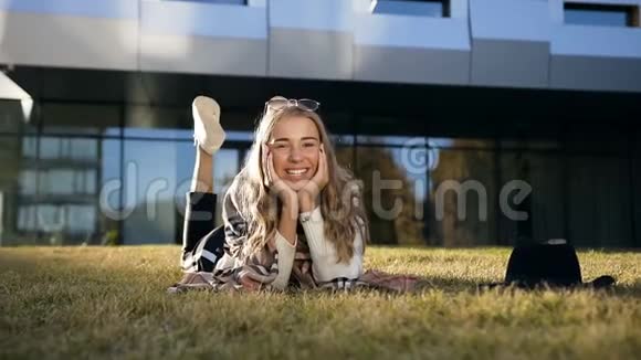 英俊时尚的女孩看着相机微笑着在草地上放松视频的预览图